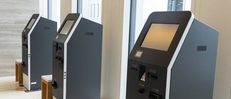 A row of self-service kiosks in a modern indoor setting with large windows.
