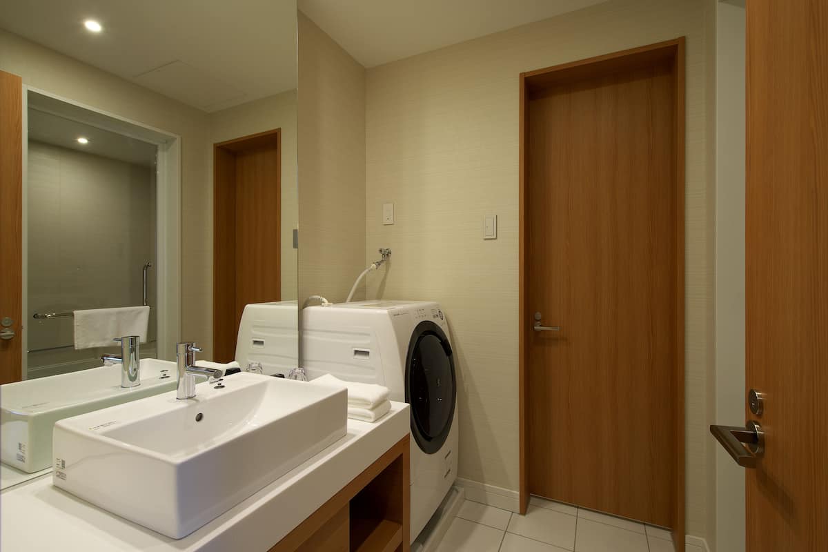 Een badkamer met een dubbele wastafel, een wasmachine en houten deuren.