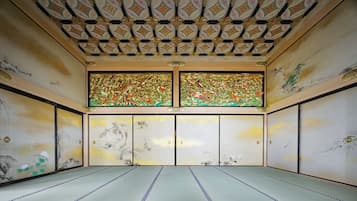 Una habitación japonesa tradicional con suelo de tatami, puertas correderas y un techo con diseños intrincados.
