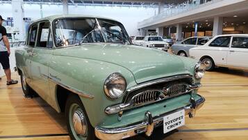 A vintage car on display in a spacious, modern indoor setting with high ceilings and a wooden floor.
