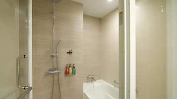 A modern bathroom with a glass shower enclosure, a white bathtub, and a wall-mounted soap dispenser.