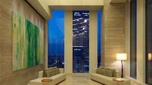 A modern lobby with a high ceiling, a unique hanging light fixture, a large abstract painting, a sofa, a coffee table, and a view of the city at night. - Nagoya JR Gate Tower Hotel (Nagoya)