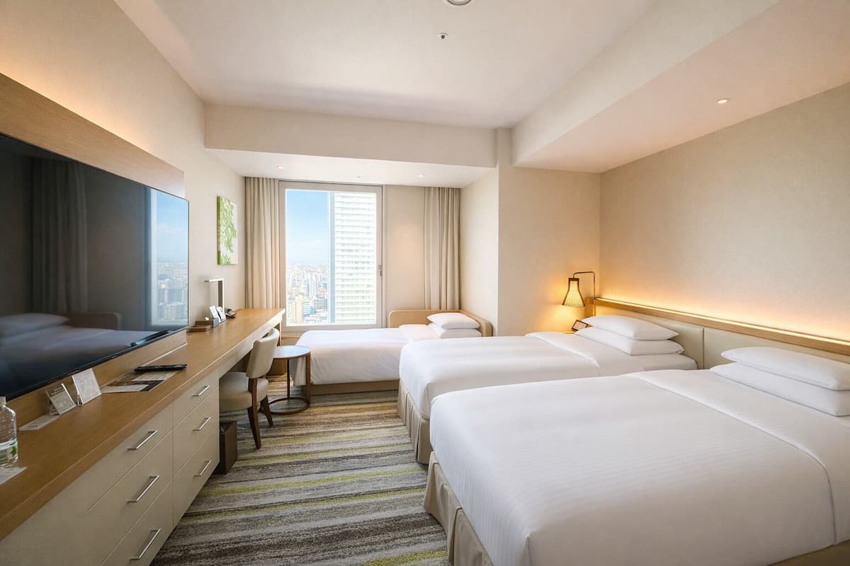 Een hotelkamer met een groot bed, een bureau met stoel, een televisie en een raam met gordijnen.