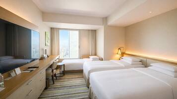 A hotel room with a large bed, a desk with a chair, a TV, and a window with curtains.