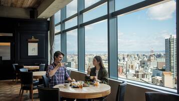 Comedor con vista a la ciudad, que incluye una mesa redonda, sillas y un menú.