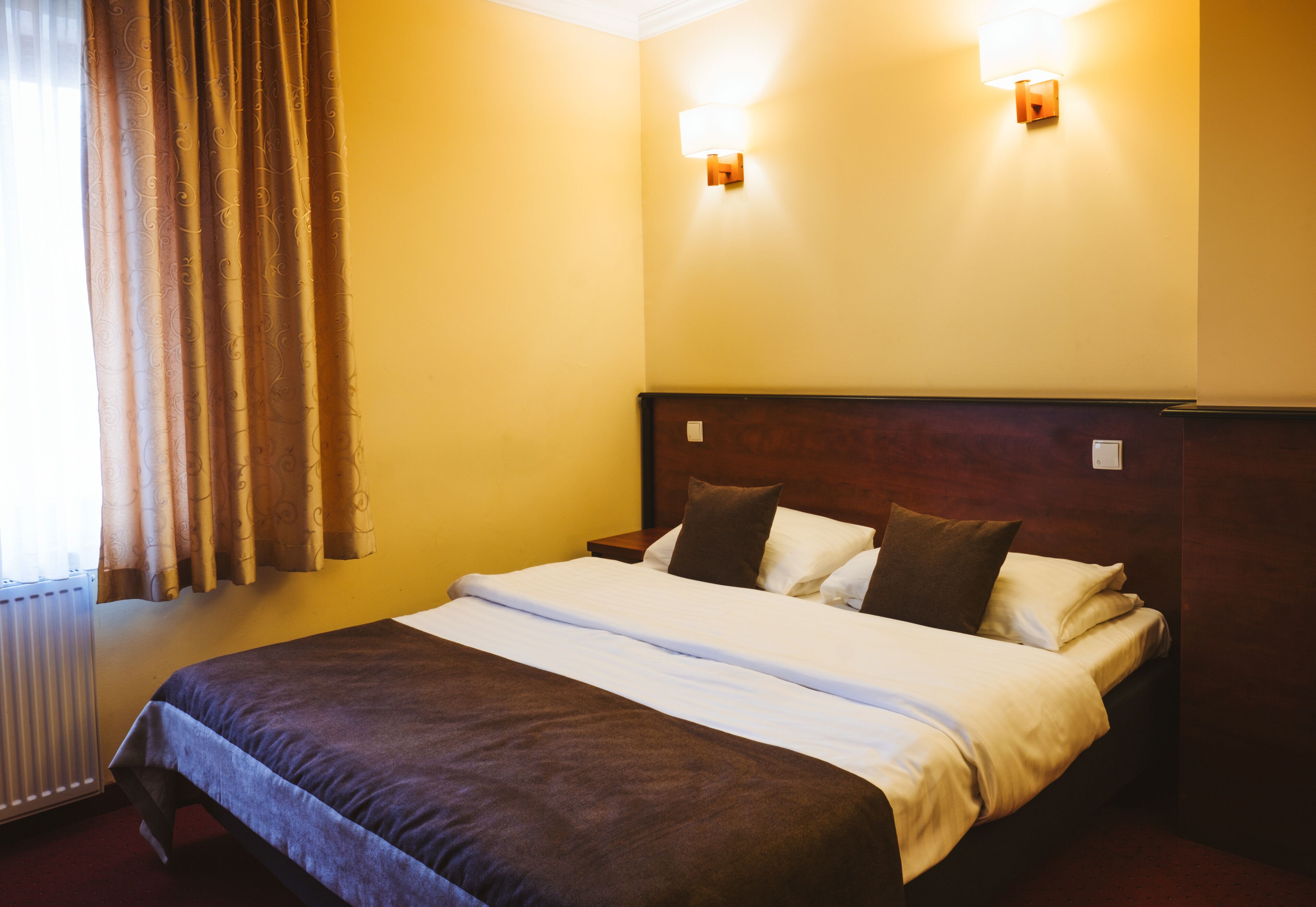 A hotel room with a large bed, two bedside tables, and a headboard.