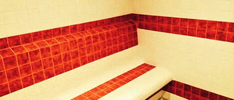 A bathroom with a red-tiled bench and white walls.