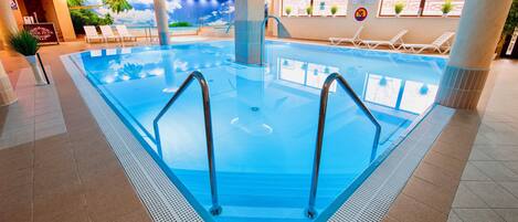 Una piscina techada, sillones reclinables de piscina