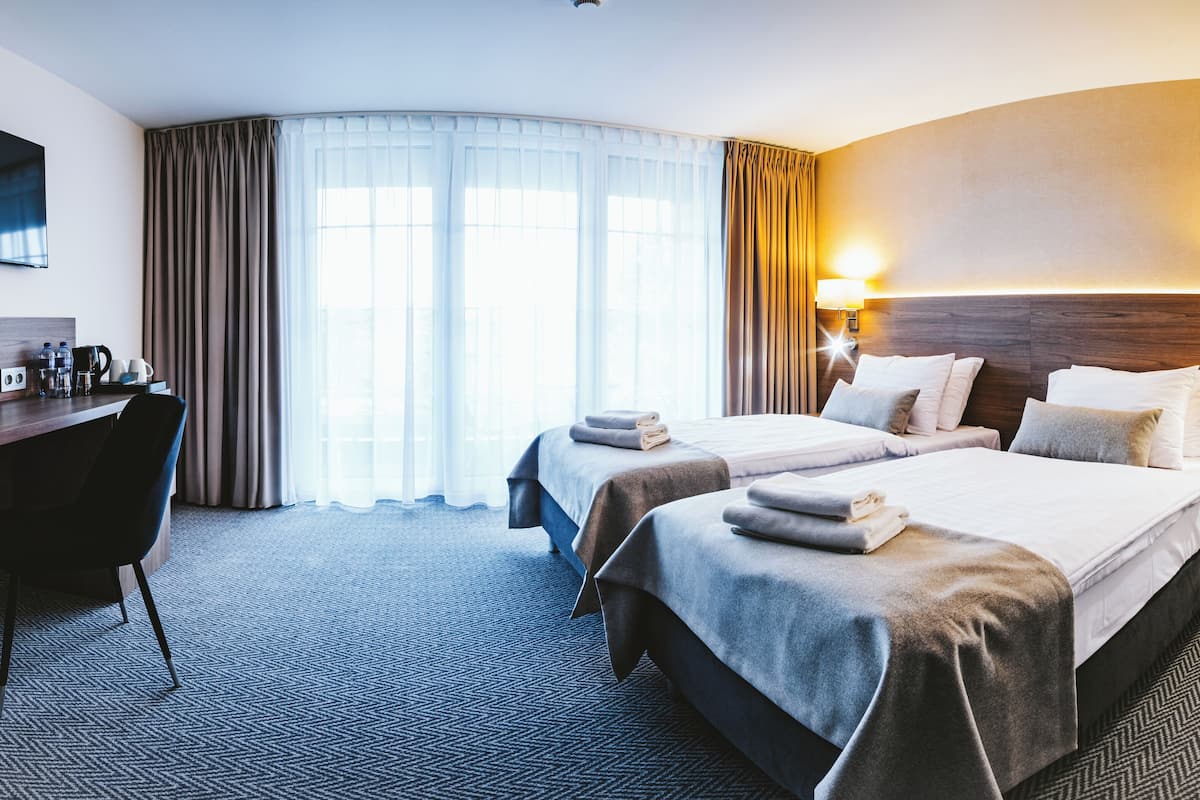Une chambre d’hôtel avec deux lits, un bureau, une chaise et un téléviseur.
