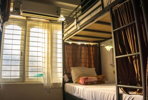 A bunk bed room with a window, curtains, and a bed with a pillow.