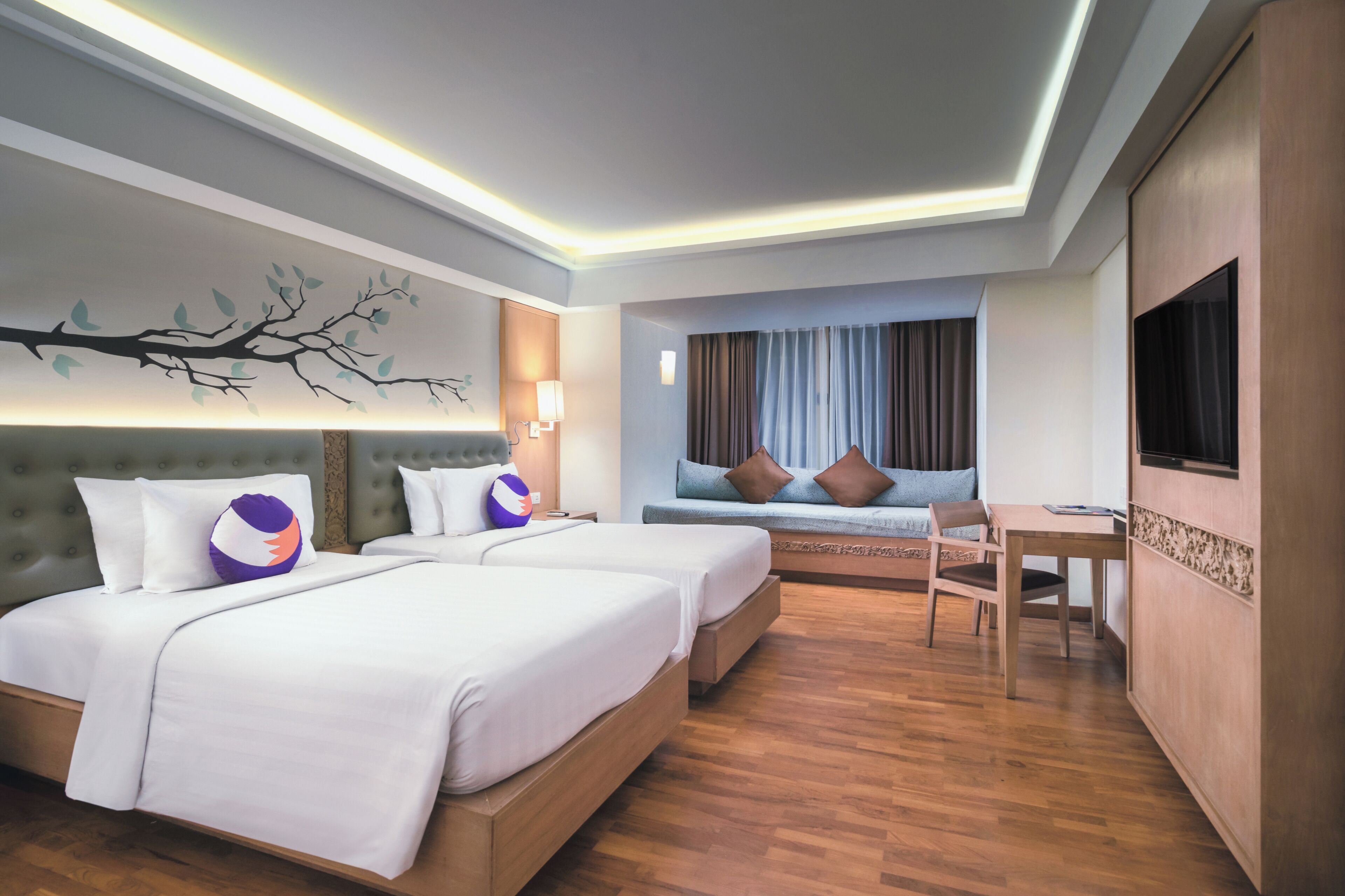 A hotel room with two beds, a sofa, a TV, and a dining table.