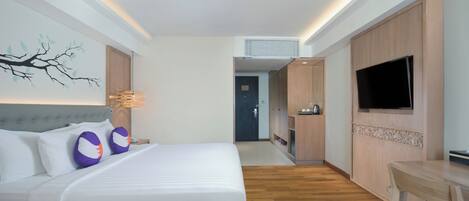 A hotel room with a bed, a TV, a desk, and a wall-mounted artwork.
