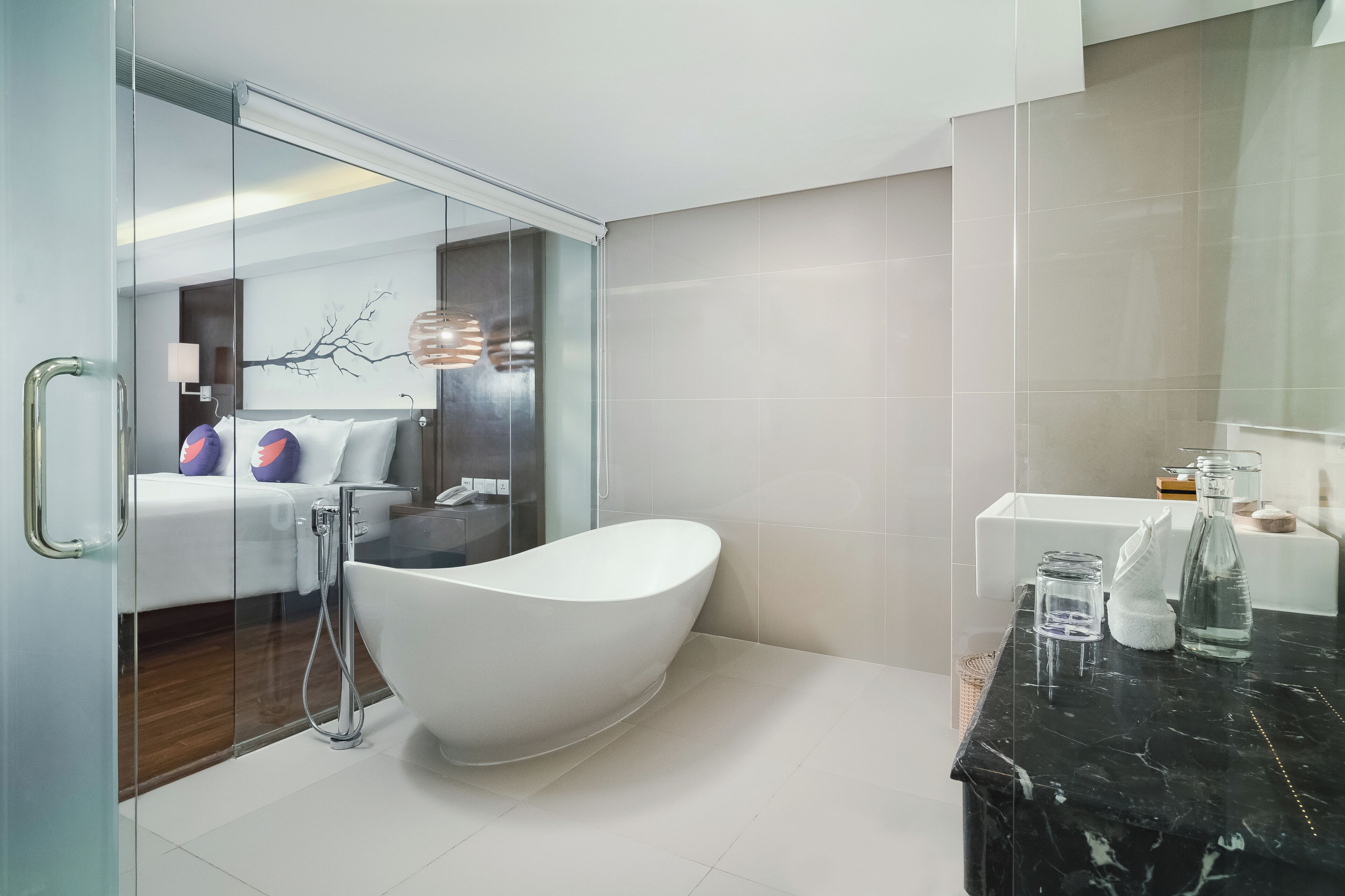 A modern bathroom with a freestanding bathtub, a glass shower enclosure, and a marble countertop with toiletries.