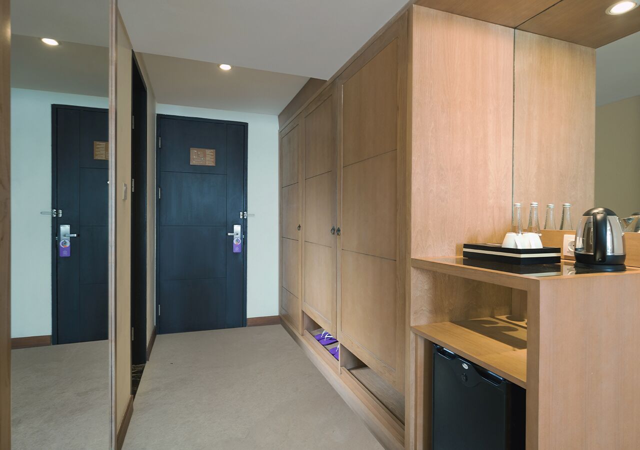 A hallway with a wooden cabinet, a coffee maker, and a black appliance, likely a dishwasher.