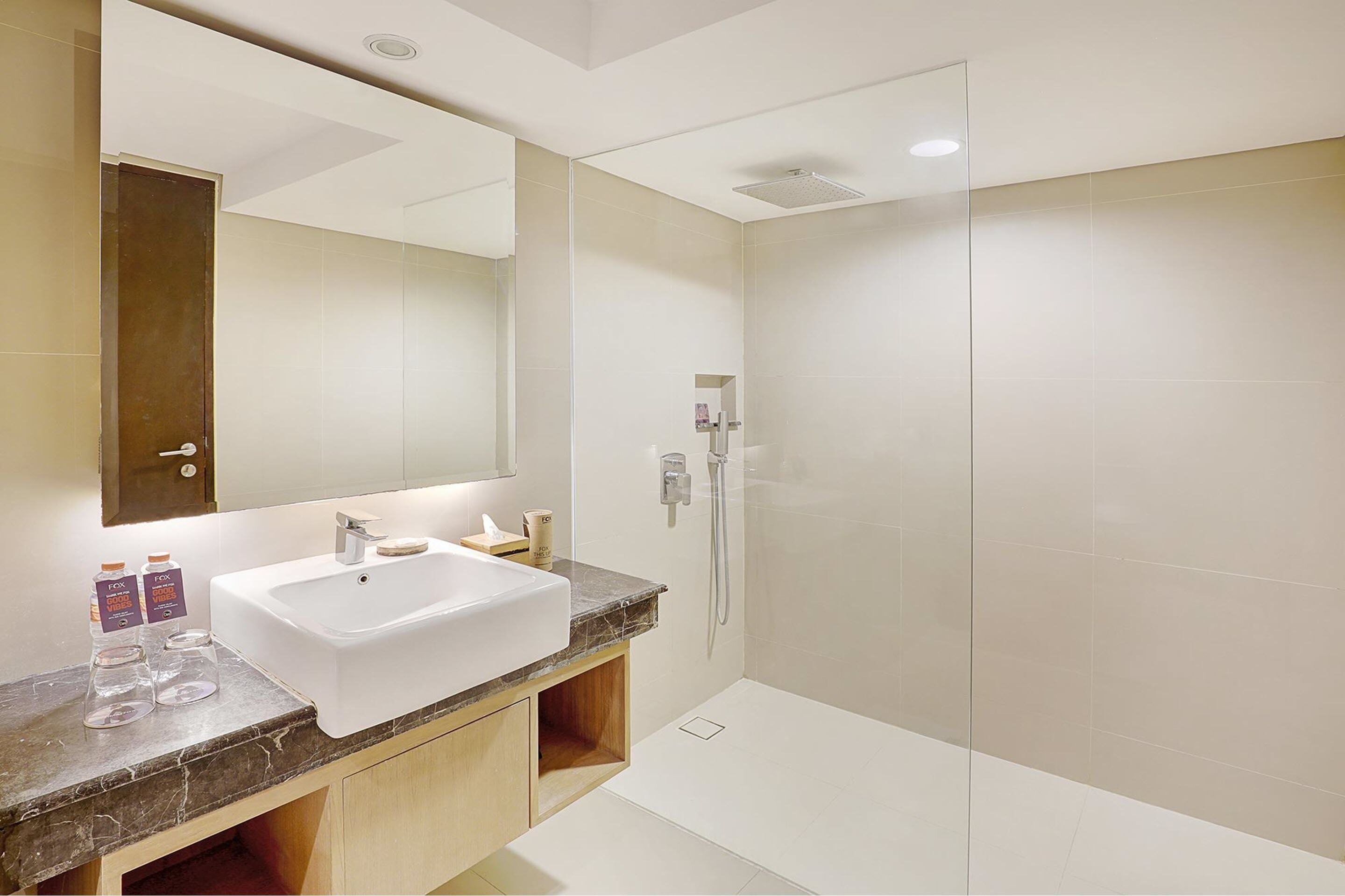 A modern bathroom with a large mirror, a sink, and a shower.
