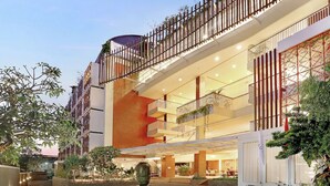 A multi-story hotel with a modern design, featuring a central atrium, multiple balconies, and a well-lit entrance area.