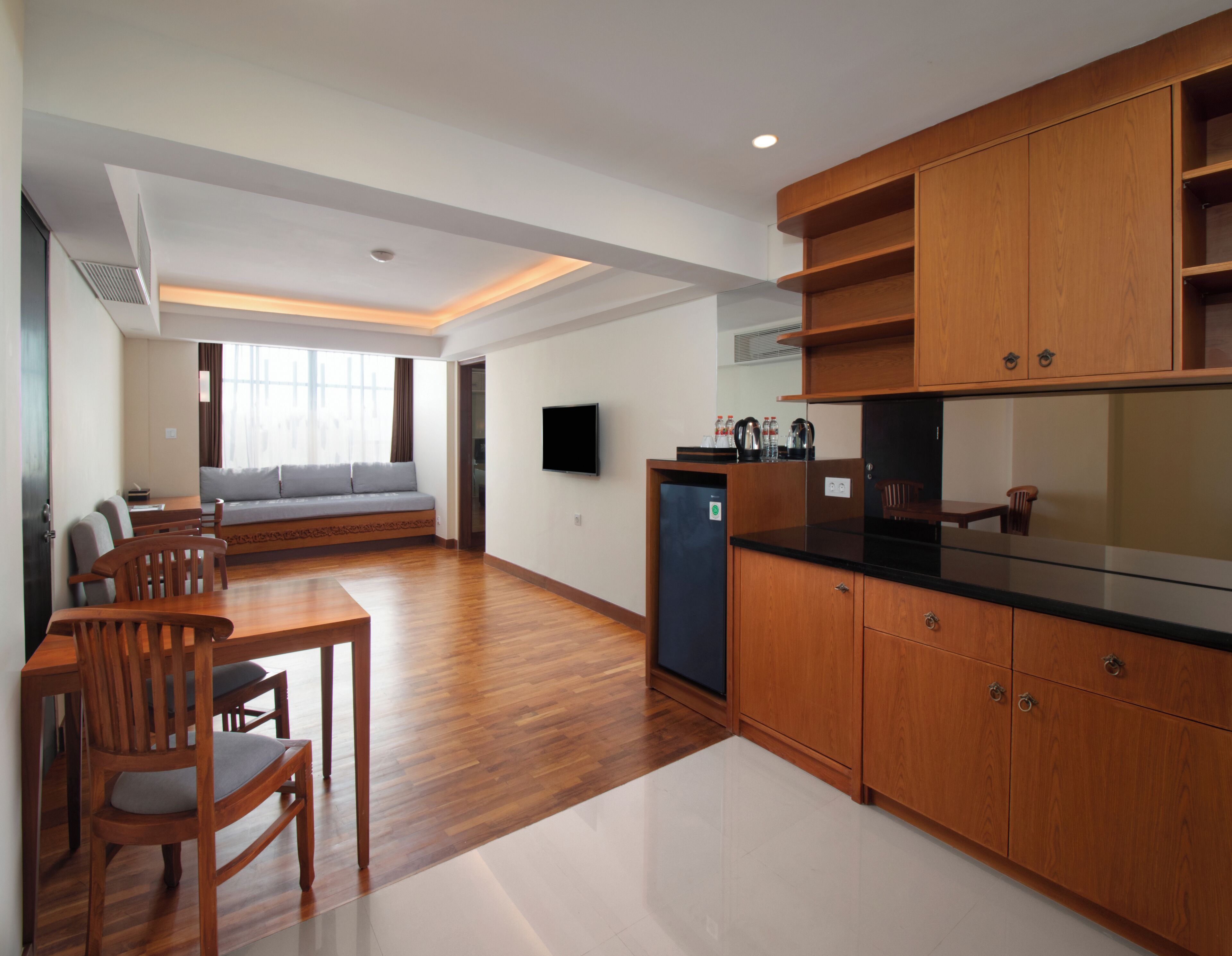A modern kitchen with wooden cabinets, a dining area with a table and chairs, and a living room with a sofa and a TV.