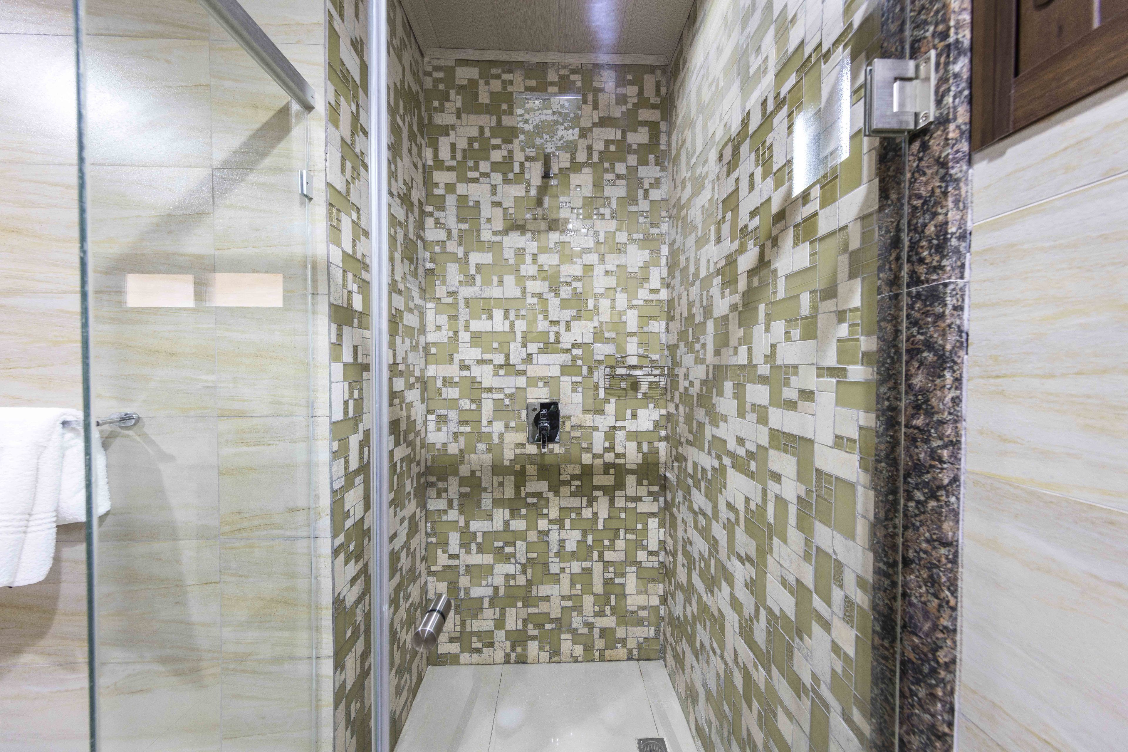 A shower with mosaic tile walls and a glass door.