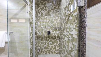 A shower with mosaic tile walls and a glass door.
