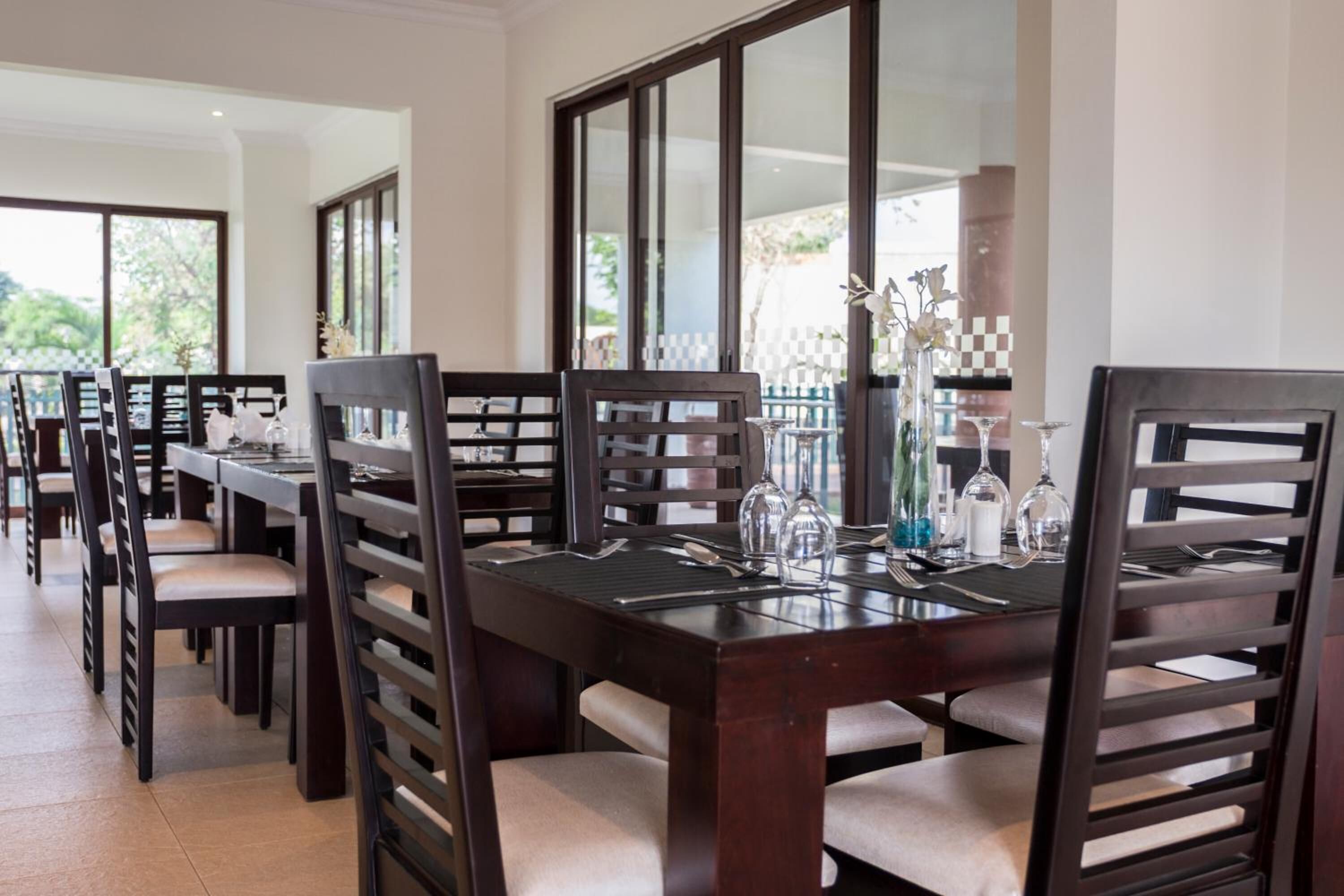 Un comedor con varias mesas y sillas, cada conjunto con cubiertos y cristalería.