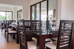 A dining area with multiple tables and chairs, each set with cutlery and glassware.