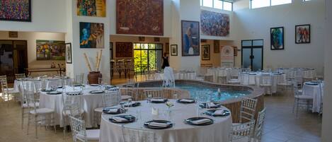 Un comedor amplio y luminoso con varias mesas redondas dispuestas para los huéspedes, rodeado de sillas transparentes.