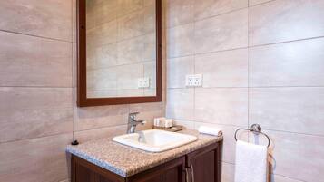 A bathroom with a granite countertop sink, a mirror, and a towel rack.