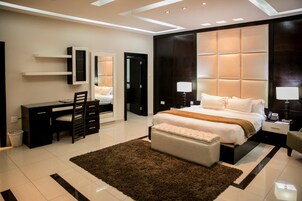 A modern bedroom with a large bed, bedside tables, a desk, and a chair.