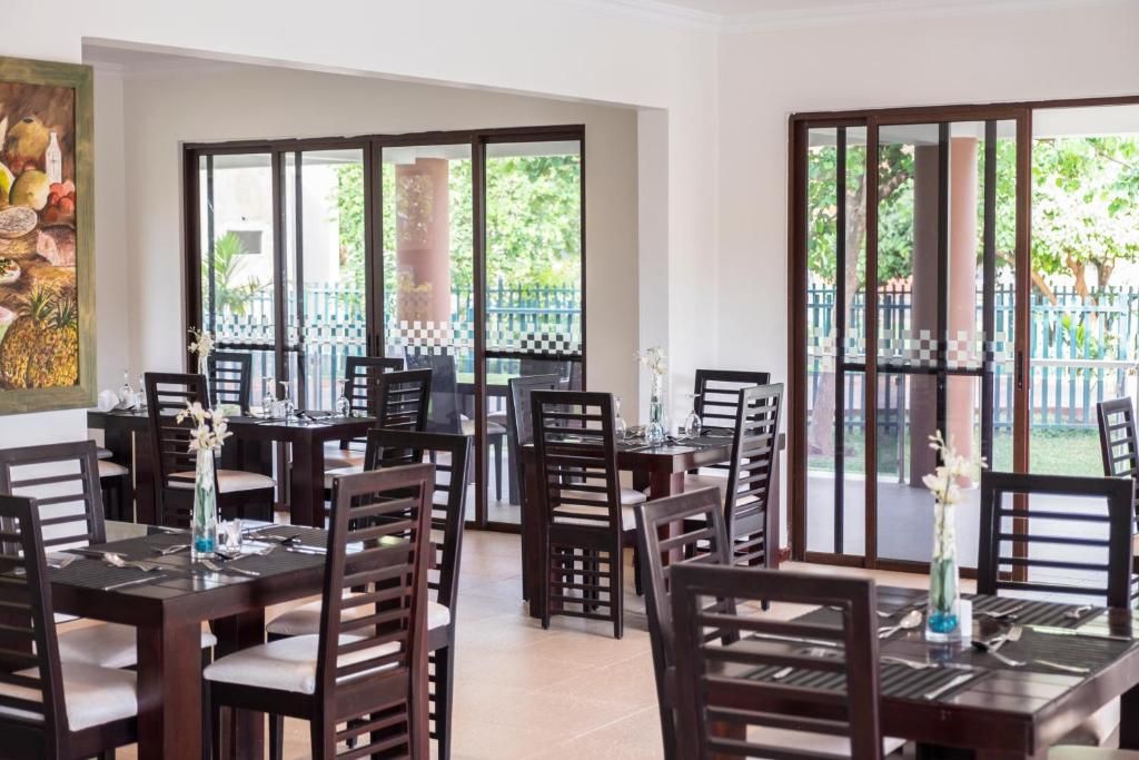 Comedor con varias mesas y sillas, ventanas amplias y vistas a zonas verdes.