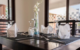 A dining table set with white napkins, clear glassware, and a vase with white flowers.