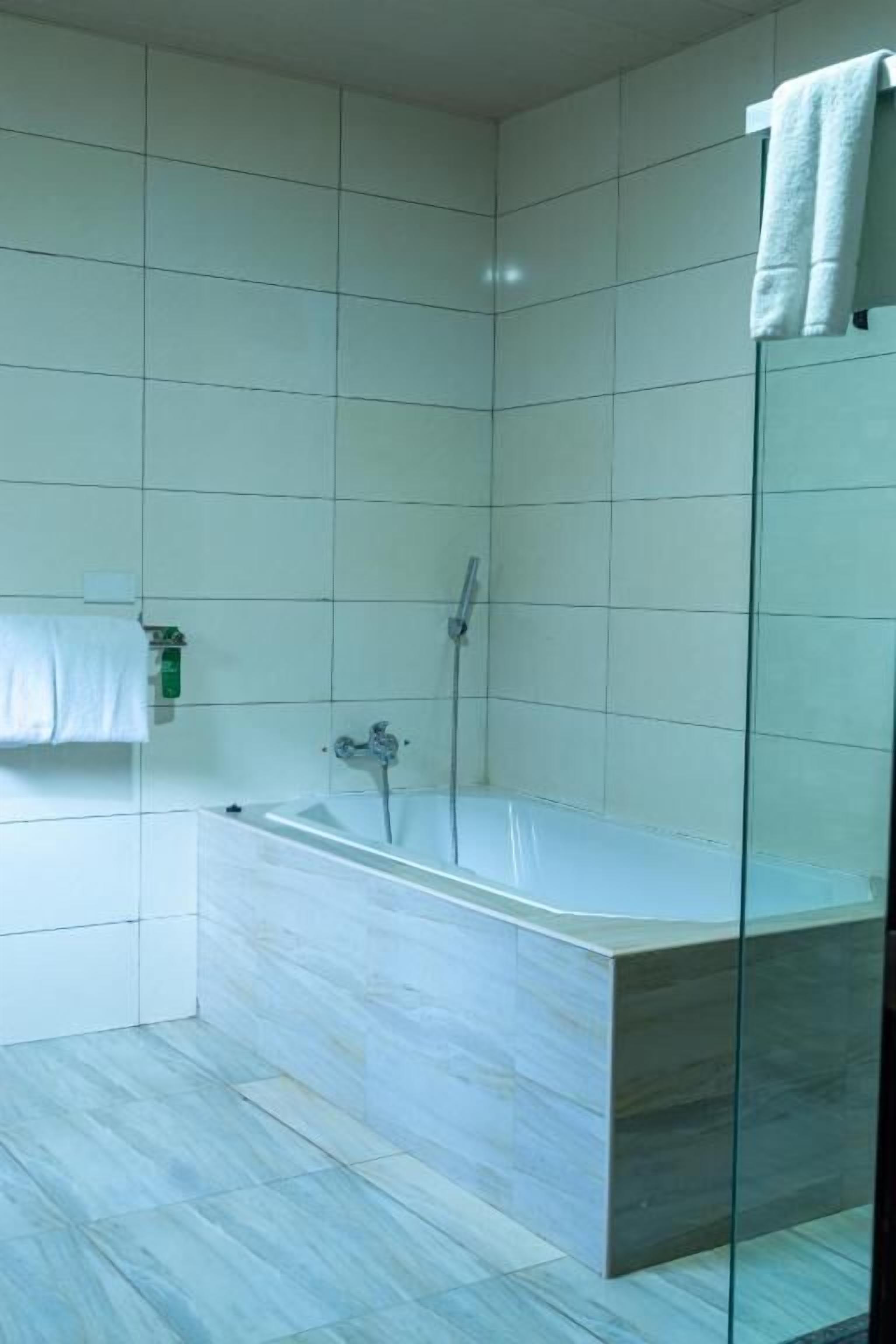 Ein modernes Badezimmer mit einer gläsernen Duschkabine, einer freistehenden Badewanne und einem weißen Handtuch an der Wand.