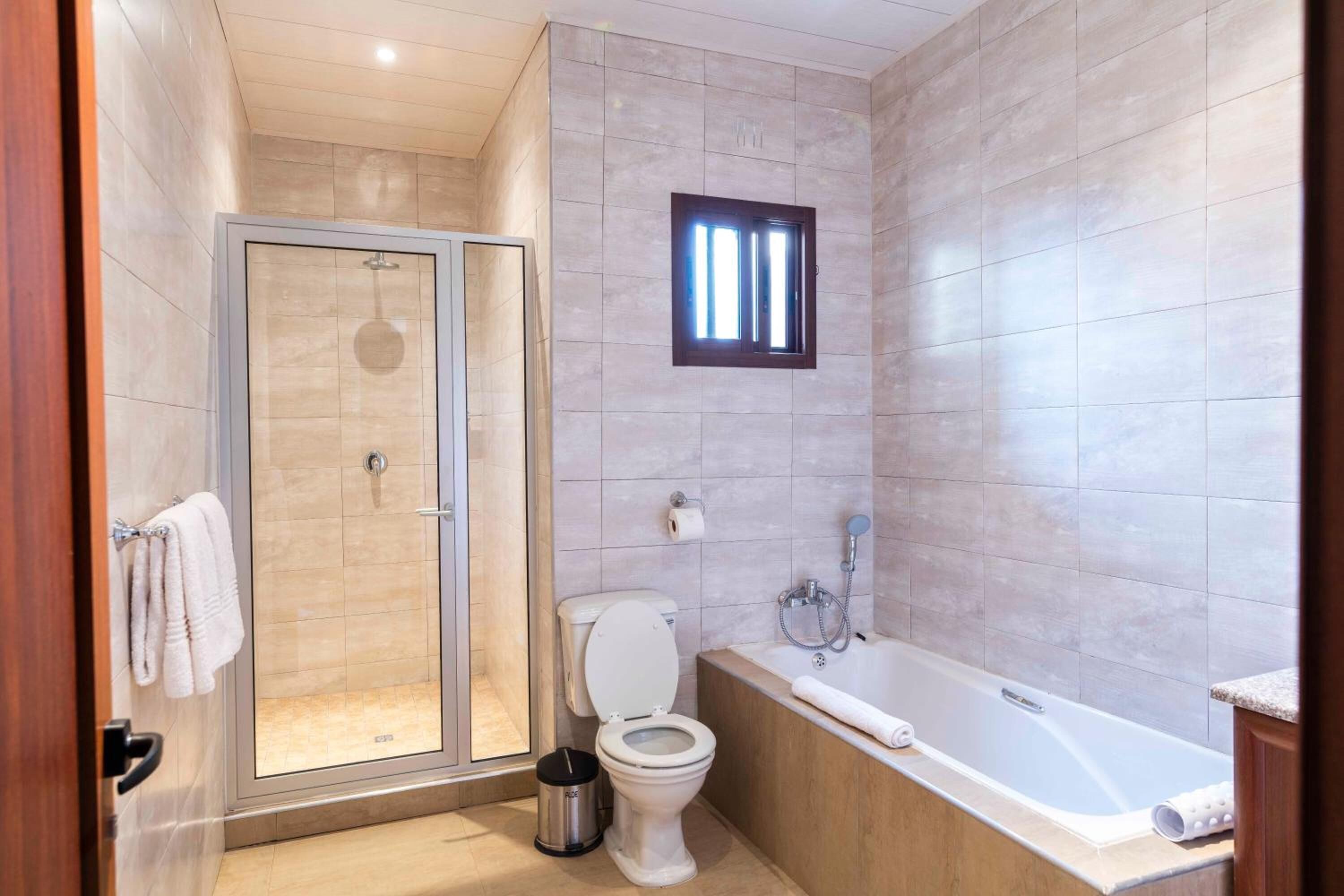A modern bathroom with a glass-enclosed shower, a toilet, and a bathtub.