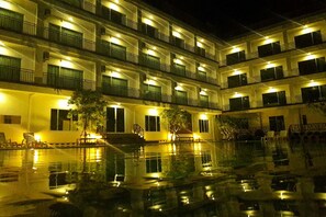 Um hotel com vários andares, varandas, piscina e área de estar ao ar livre.