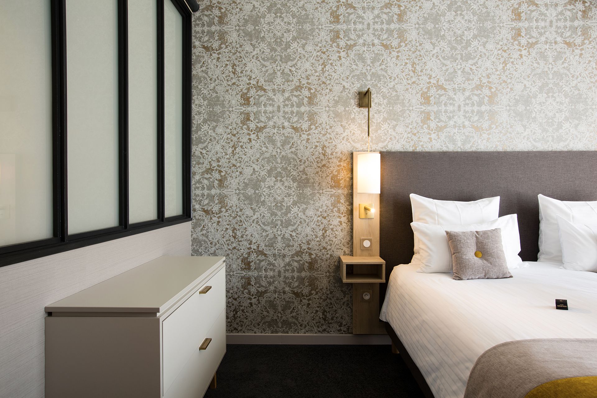 Une chambre d’hôtel avec un lit, une table de chevet et un petit placard.