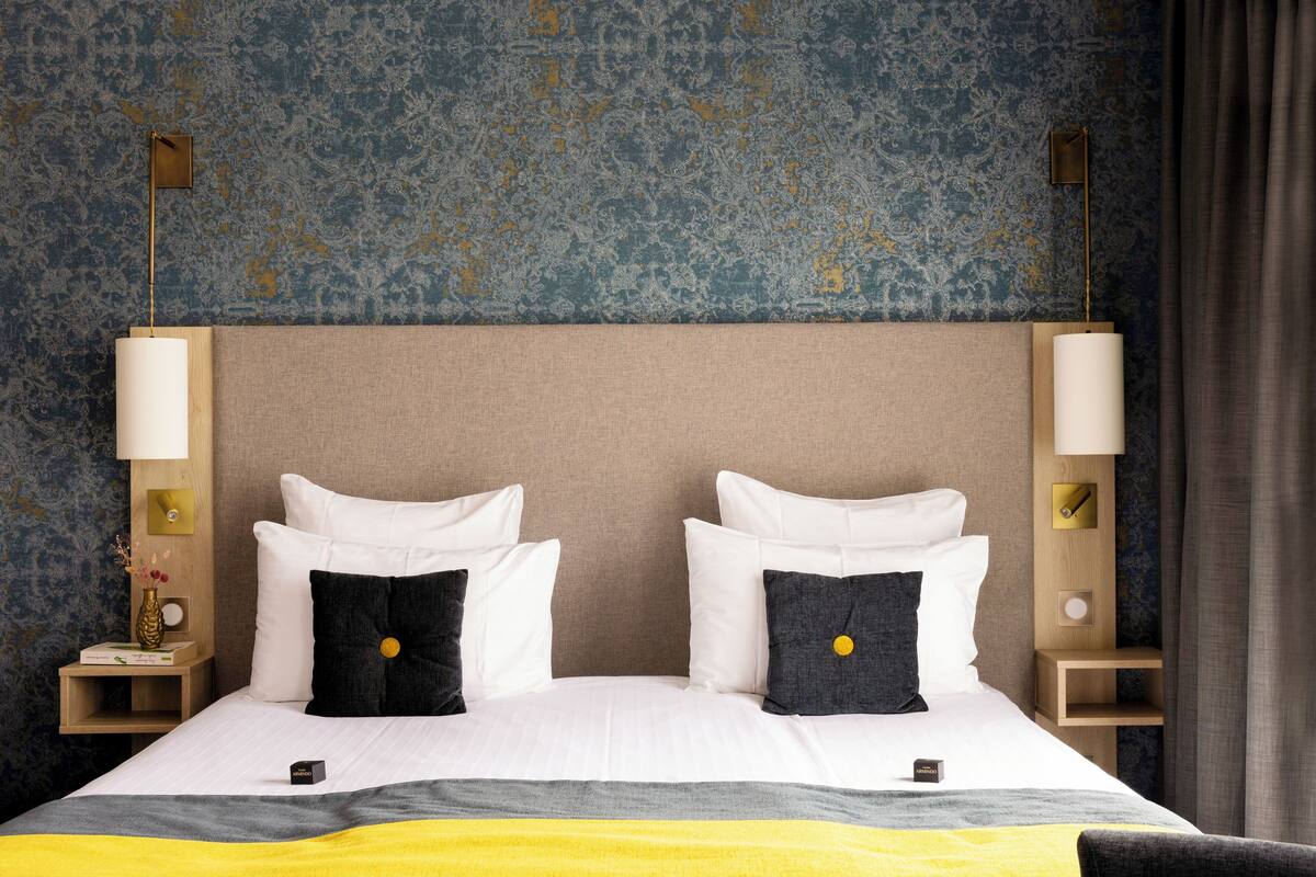 A hotel room with a large bed, two bedside tables, and a nightstand with a lamp.