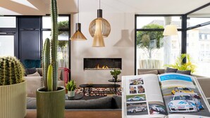 A modern living room with a fireplace, a sofa, a coffee table, and two potted cacti. - James Boutique Hôtel (Colmar)