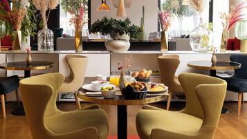 A dining area with a round table, four chairs, and a variety of breakfast items.