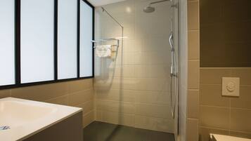 Une salle de bain moderne avec une grande baignoire, une douche à l’italienne et des toilettes.