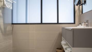A modern bathroom with a large window, a sink, and a mirror.