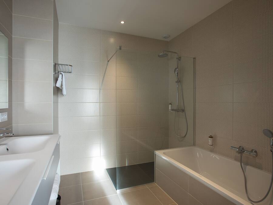 Un baño moderno con una bañera grande, una zona de ducha separada y un tocador con espejo.