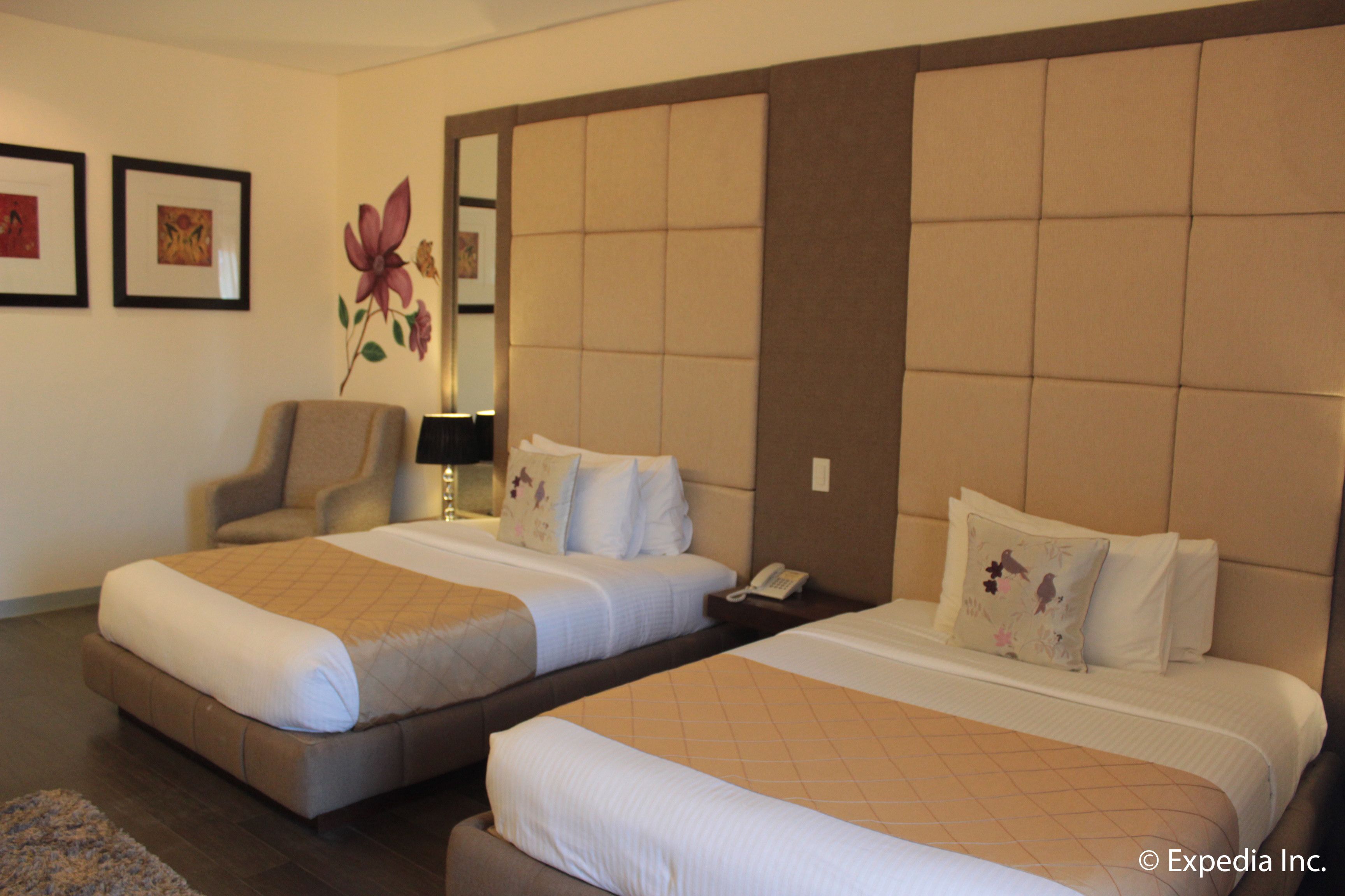 A hotel room with two beds, a chair, and a mirror.