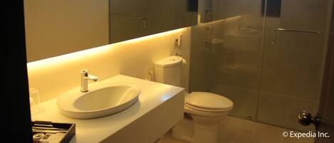 A modern bathroom with a sink, toilet, and glass-enclosed shower.