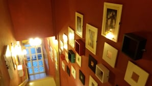 A staircase with a handrail, leading to a room with a red wall adorned with framed pictures. - City Inn Hotel (Kuala Lumpur)