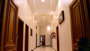 A hallway with wooden doors and a fire extinguisher on the wall. - La Posh Hotel (Kigali)