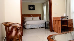 A hotel room with a wooden bed, a small desk, a chair, and a glass table. - La Posh Hotel (Kigali)