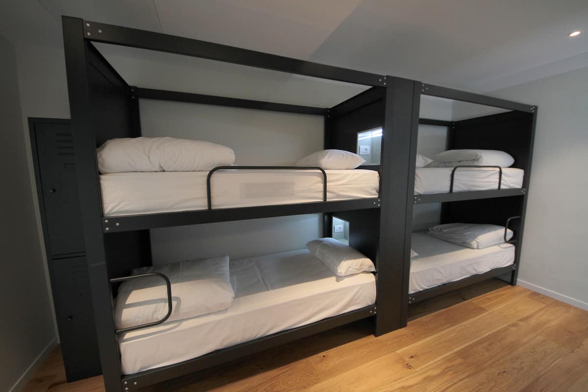 Una cama litera con tres niveles, cada uno con un colchón y almohadas.
