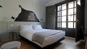 A bedroom with a bed, bedside table, and a wall-mounted artwork. - Complutum Hostel (Alcala de Henares)