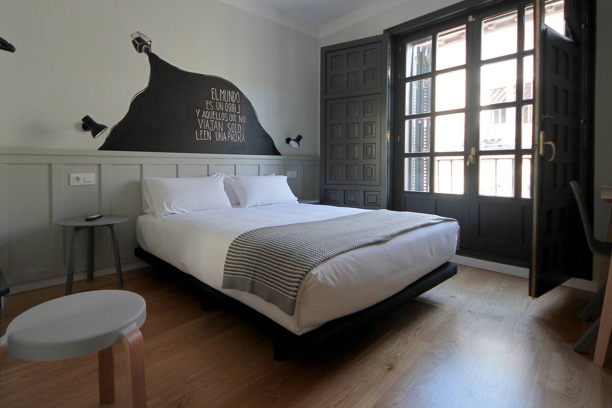 Un dormitorio con cama, mesita de noche y una obra de arte en la pared.