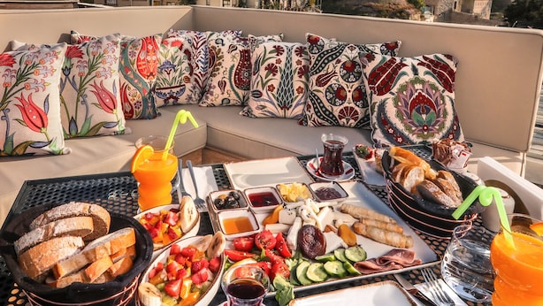 A rooftop dining area with a view of historic buildings, a variety of foods, and a table set for two. - Henna Hotel Istanbul (Istanbul)