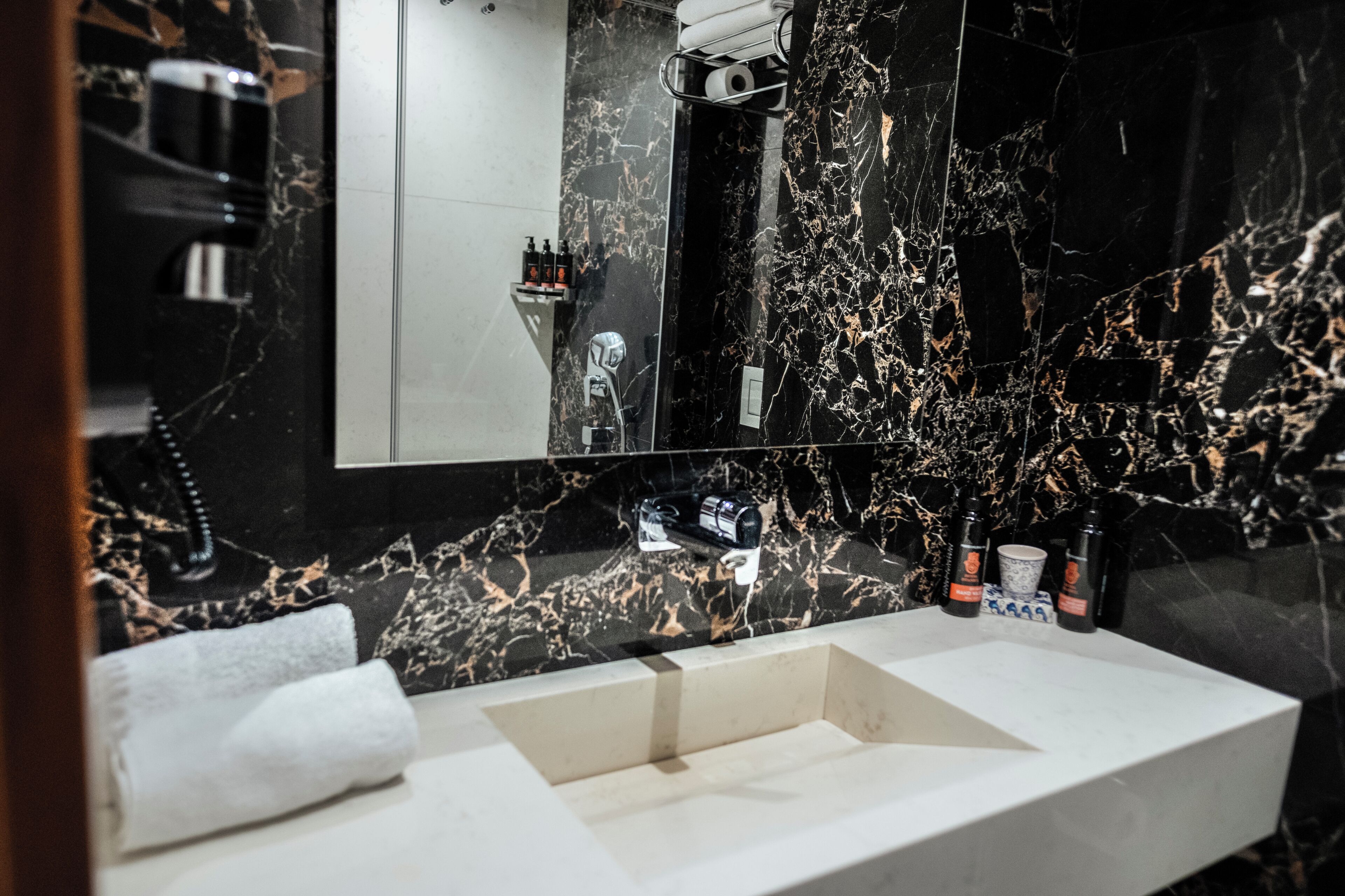 A modern bathroom with a marble sink, a large mirror, and toiletries on the counter.